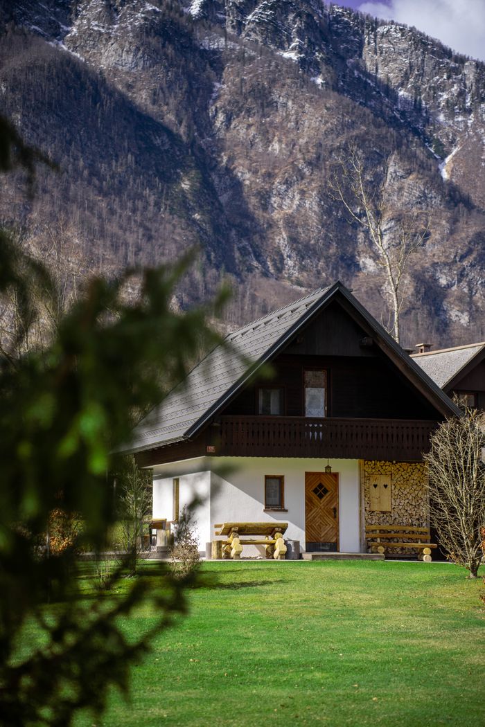 Wooden chalet nestled in the mountains of Slovenia, showcasing beautiful greenery and a tranquil setting.