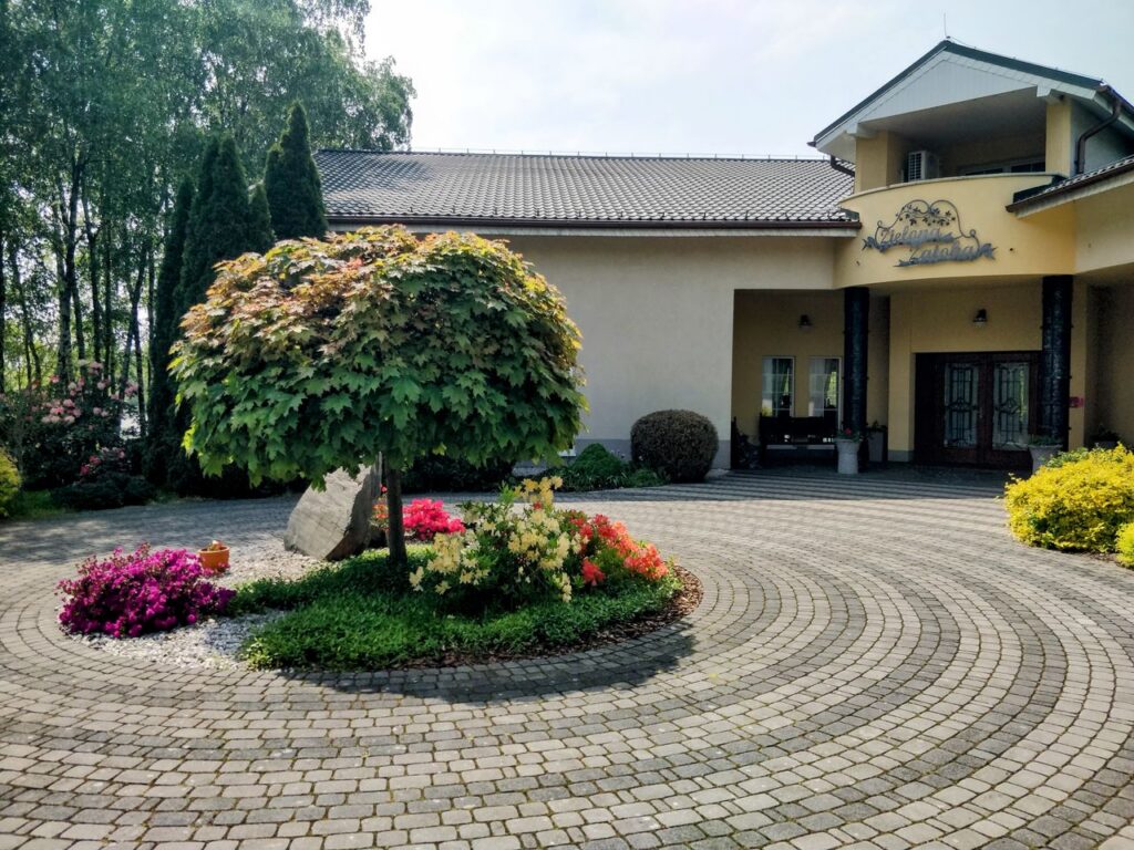 Beautiful inn entrance surrounded by lush gardens and colorful flowers on a sunny day.
