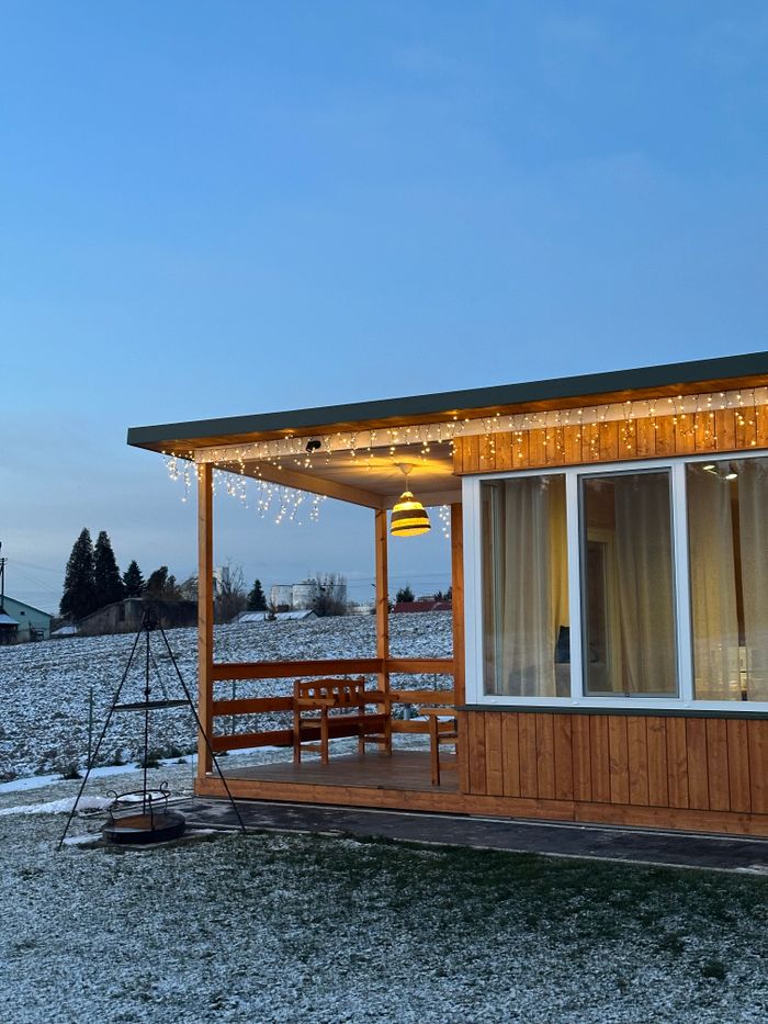 Wooden cabin adorned with festive lights during a serene winter evening, showcasing rural charm.