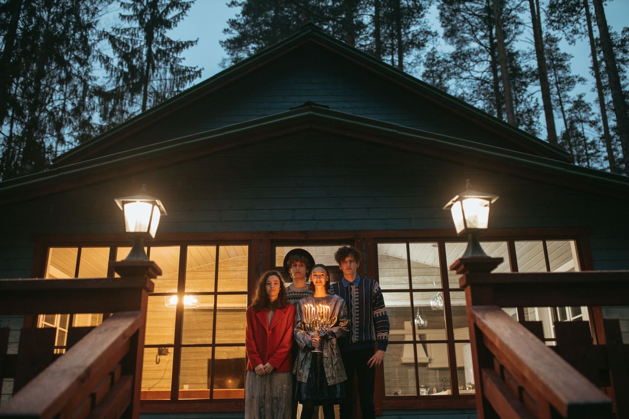 A group of friends celebrating Hanukkah with a menorah on a cabin porch.